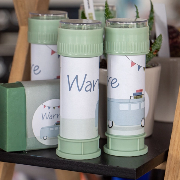 Bellenblazers met een gepersonaliseerde sticker in dezelfde stijl als het geboortekaartje van Warre. Er staat de naam Warre op en de illustratie van de camper met vlaggenlijn.
