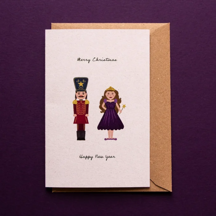 Kerstkaart Clara en de Notenkraker met een illustratie van de Notenkraker in uniform en Clara als suikerfee en de tekst: Merry Christmas, Happy New Year.