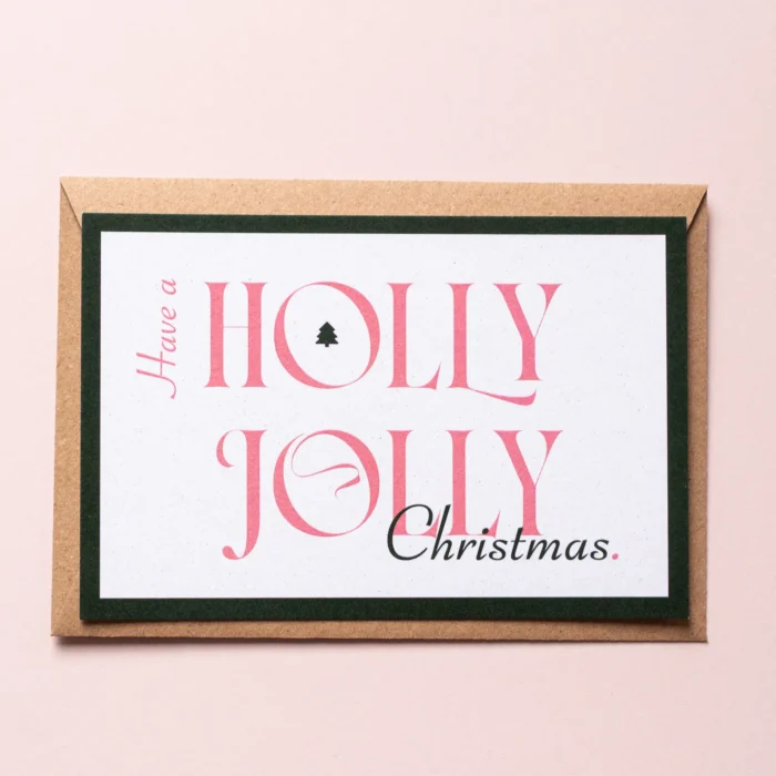 Kerstkaart Holly Jolly met donkergroene rand en de tekst: Have a holly jolly Christmas. In de 'O' van Holly staat een kleine illustratie van een kerstboom. Het is een speels, typografisch ontwerp.