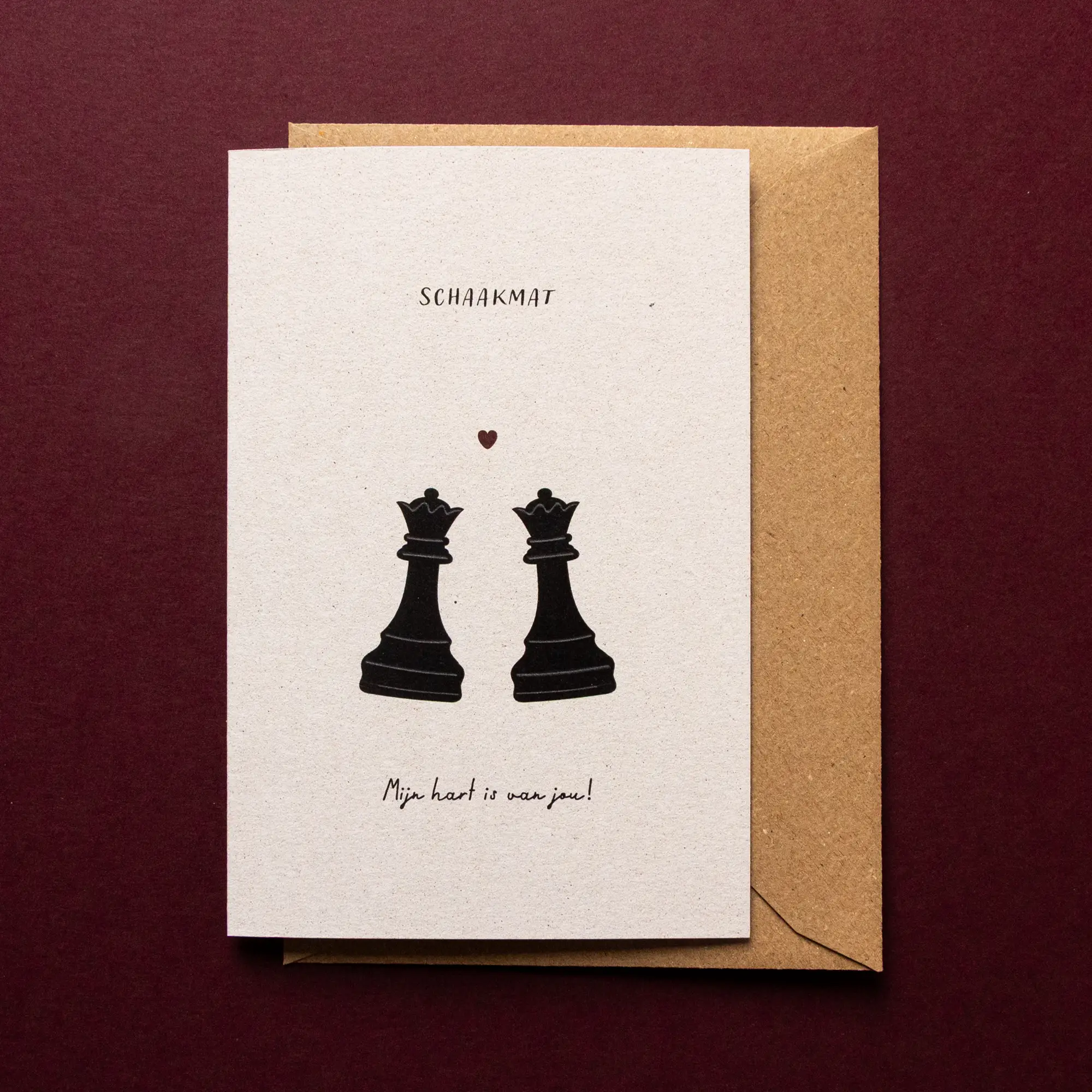 Liefdeswenskaart Schaakmat met illustratie van twee zwarte koninginnen uit een schaakspel met een klein rood hartje en de tekst: 'Schaakmat, mijn hart is van jou!'.