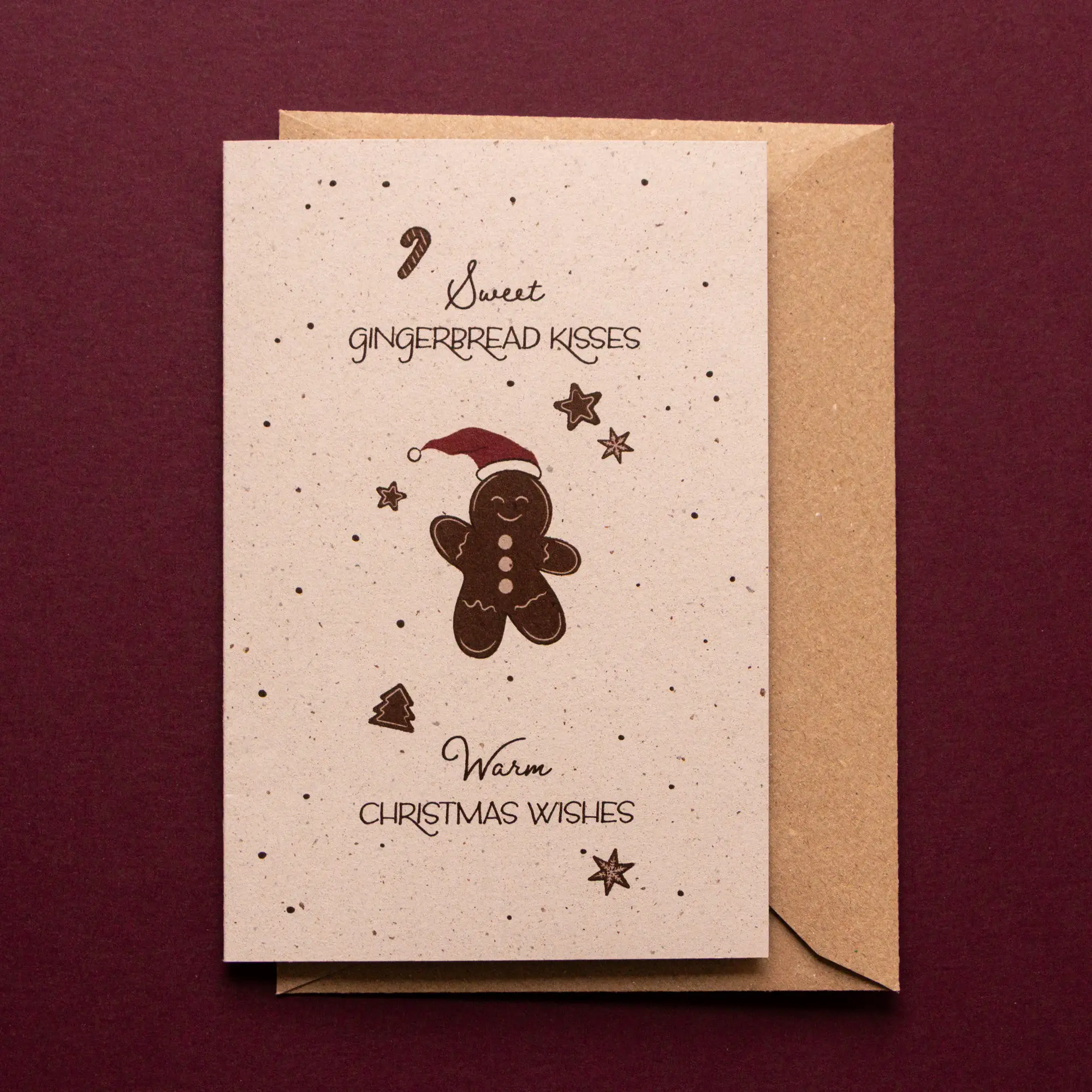 Kerstkaart Peperkoekmannetje met illustraties van een lachend peperkoekmannetje, kleine, zwevende koekjesfiguren en kruimels. De kerstwens op deze kaart luidt: sweet gingerbread kisses, warm christmas wishes.
